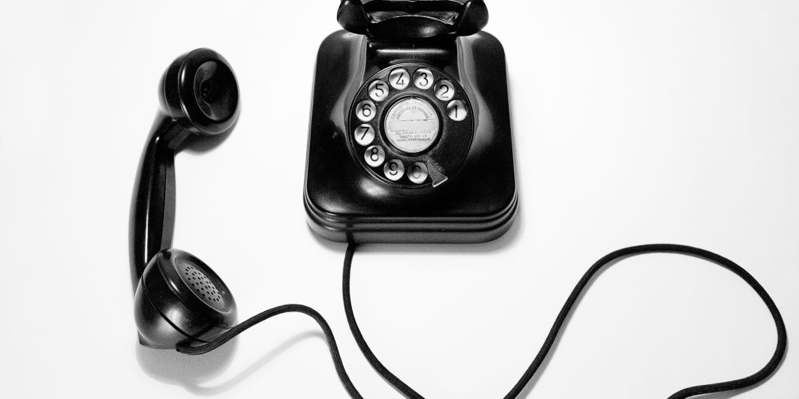 black rotary dial phone on white surface