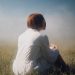 woman in white long sleeve shirt sitting on green grass field during daytime