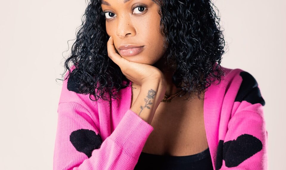 a woman in a pink cardigan leaning on a chair